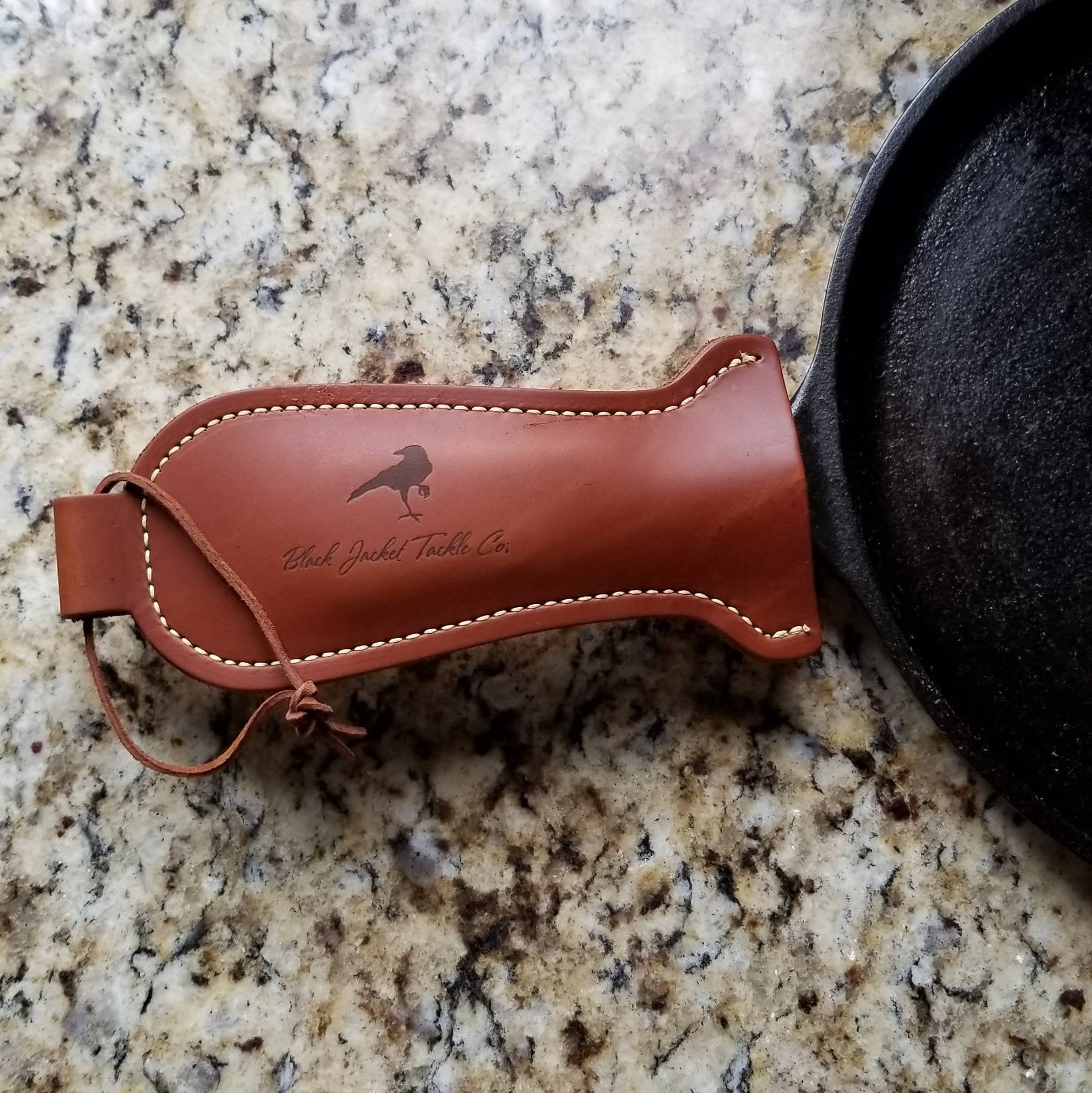 Close up of brown leather handle holder on a cast iron grill pan