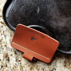 Brown leather handle holder shown on a cast iron reversible griddle pan