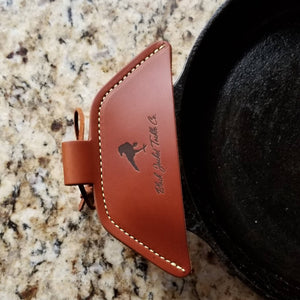 Brown leather assist handle holder shown on assist handle of cast iron skillet