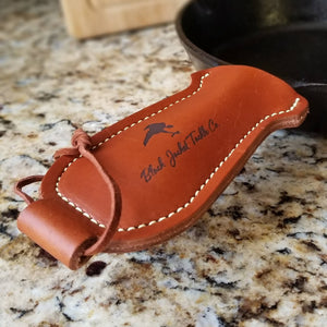 Brown leather pan handle holder shown on cast iron skillet